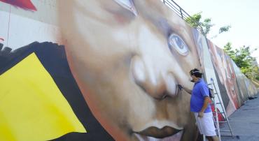 Artista grafita rosto de criança em muro