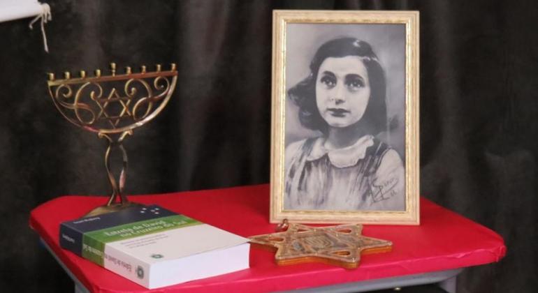 Menorá. o candelabro judeu de sete braços, a estrela de David, símbolo judaico, a foto de Anne Frank, criança judia que escreveu um diário, e uma edição recente de seu diário.