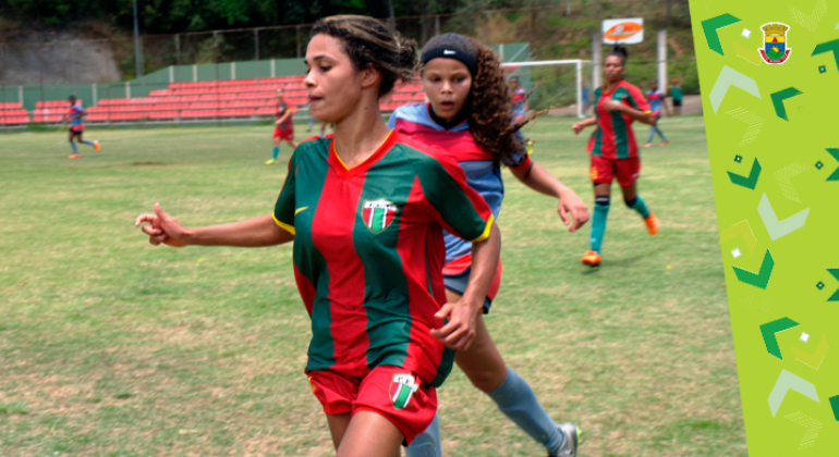 Três garotas jogam futebol.