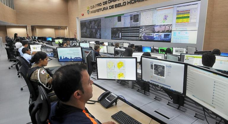 Mais de doze pessoas diante dos computadores do Centro de Operações da PBH (COP BH), trabalhando.