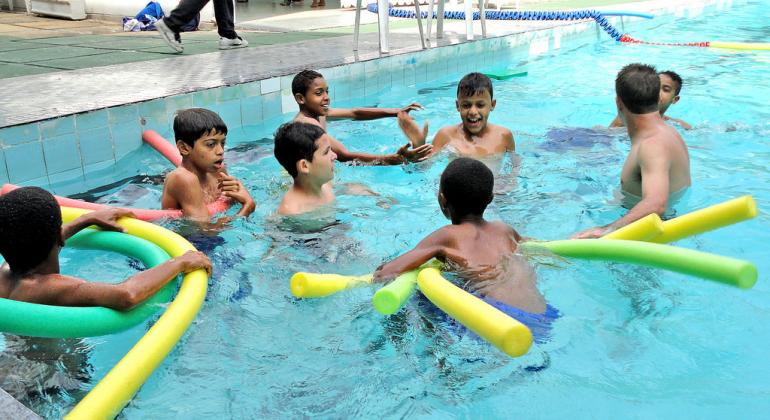 Oito meninos estão na piscina brincando com boias