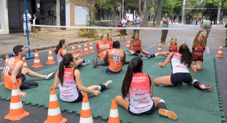 Tome misto de vôlei sentado jogando com adversários.