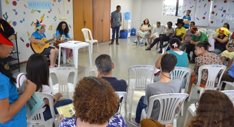 Dupla musical faz apresentação com violão a pais, responsáveis e pessoas com deficiência. 