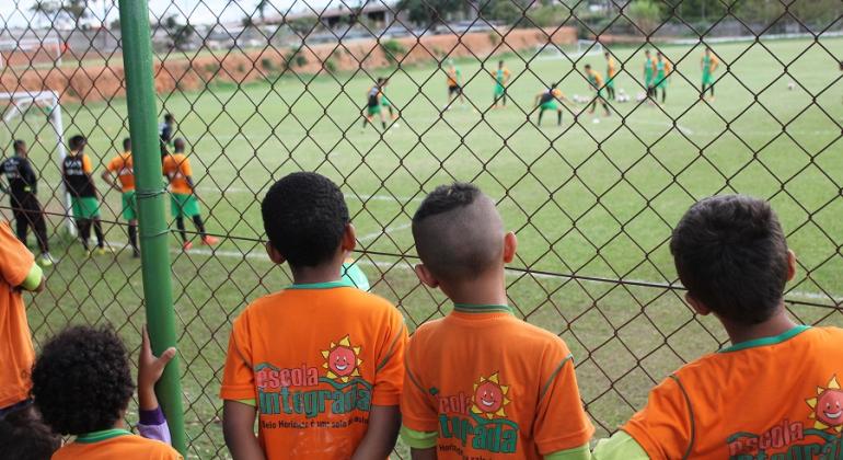 Quatro estudantes de escola municipal observam jogadores no Centro de Treinamento do América. 