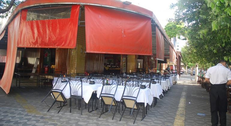 Bar de esquina com messa arrumadas e espaço para trânsito de pedestres