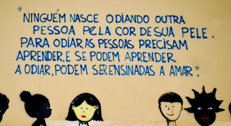 Na parte de baixo de uma parede foram desenhadas quatro pessoas, duas delas negras, uma branca e uma com o rosto amarelo. Acima, os dizeres: "Ninguém nasce odiando outra pessoa pela cor de sua pele. Para odiar as pessoas precisam aprender, e se podem aprender odiar, podem ser ensinadas a amar.