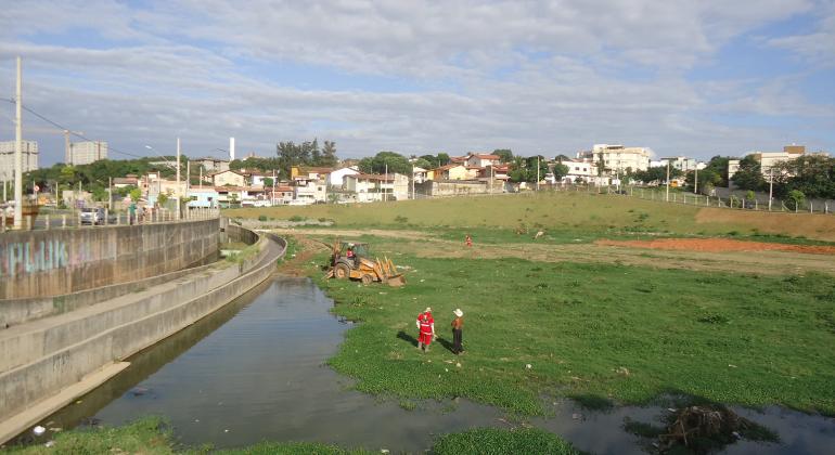 Funcionários da PBH limpam o córrego Várzea da Palma durante o dia.