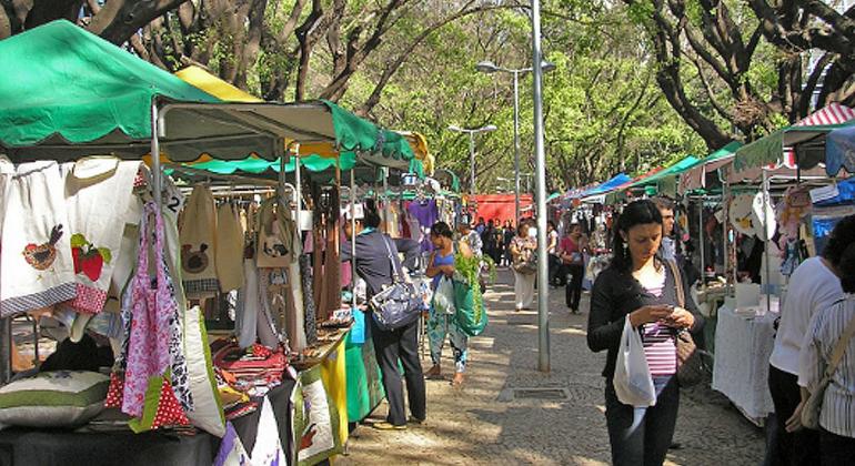 Cerca de cinco homens e mulheres passeiam nas mais de dez barraquinhas da feira de artesanato da avenida Bernardo Monteiro. 