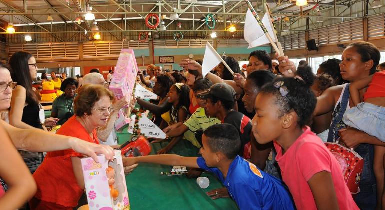 Funcionários de Restaurante Popular entregam brinquedos a crianças em almoço de Natal.