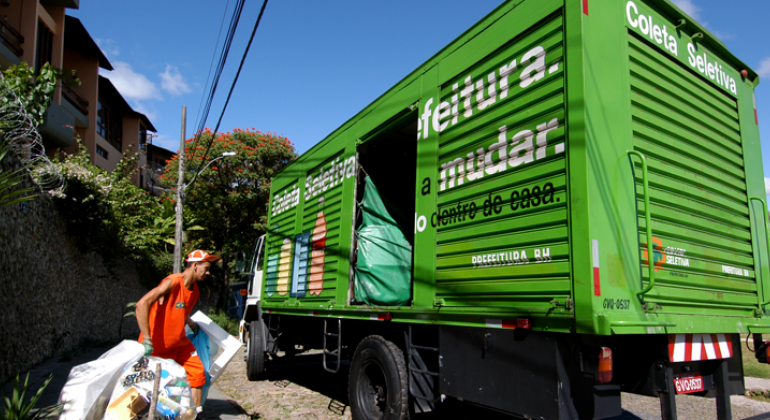 Funcionário da SLU coloca sacos de lixo em caminhão da coleta seletiva. 