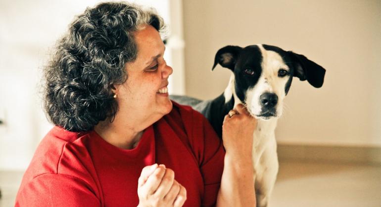 Cidadã sorri para cãozinho que adotou.