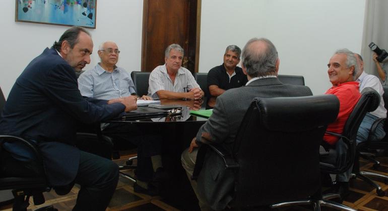 O prefeito de Belo Horizonte, Alexandre Kalil, os secretários municipais de Saúde, Jackson Machado, e de Fazenda, Fuad Noman, e representantes da Maternidade Sofia Feldman, sentados em uma mesa oval, coversando. 