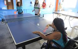 Duas garotas jogam pingue-pongue, uma delas é cadeirante.