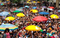Multidão de foliões e ambulantes em bloco de carnaval.