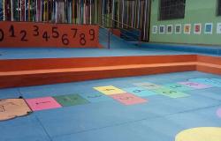 Pátio de escola municipal que atende a Educação Infantil, com chão pintado com o jogo da amarelinha em cores diversas.